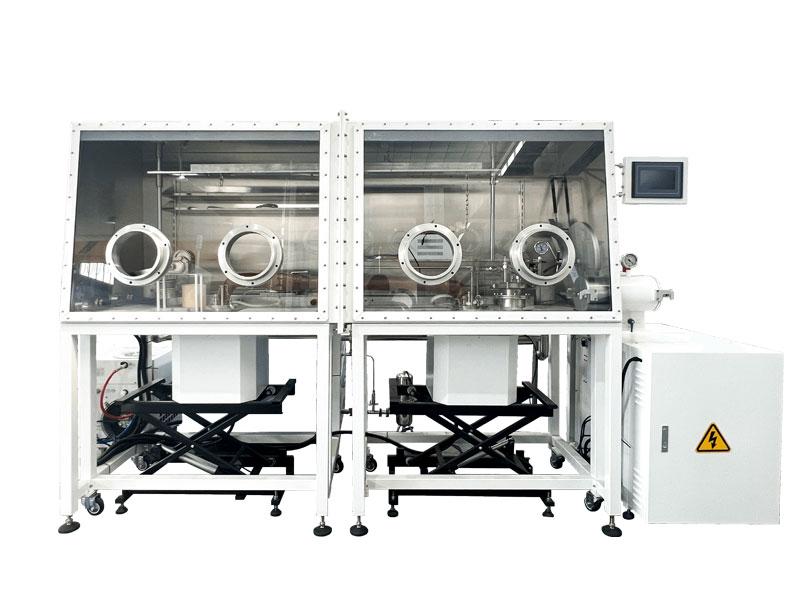 A dual-station inert atmosphere glovebox system on a mobile white frame. Each station features a stainless steel chamber with a clear front panel, and is positioned above a black scissor lift for material loading and unloading. The unit includes a touchscreen control panel and a main electrical cabinet.